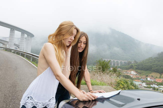 Duas meninas olhando no mapa na estrada — Fotografia de Stock