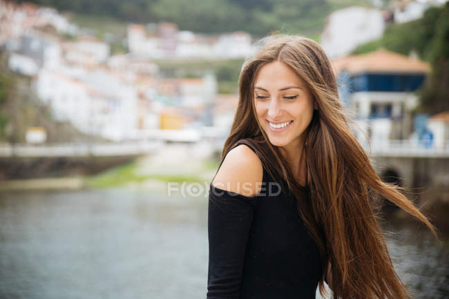 Sonriente chica morena contra ciudad borrosa - foto de stock