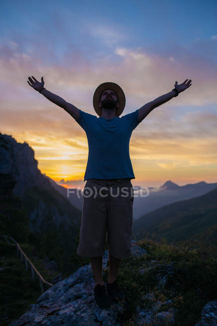 Man with hat posing over epic mountains sunset — Stock Photo