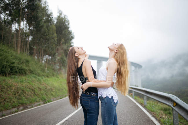 Two girls posing on foggy road. — Stock Photo