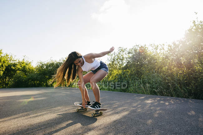 Adolescent équitation skateboard dans sunlight — Photo de stock