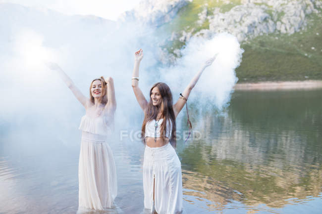 Dos chicas con bengalas posando en el lago - foto de stock