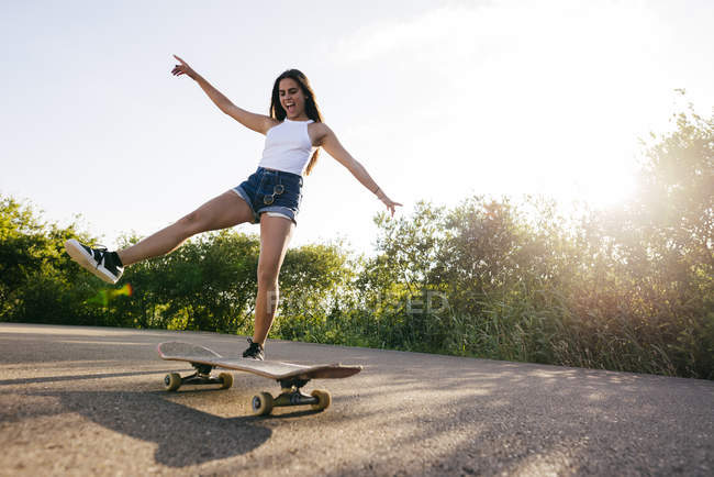 Chica montando skate alegremente - foto de stock