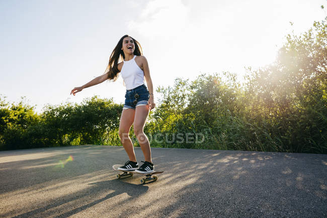 Teen riding skateboard in sunlight — Stock Photo