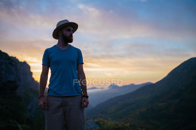 Mann mit Hut posiert über Sonnenuntergang am Berg — Stockfoto