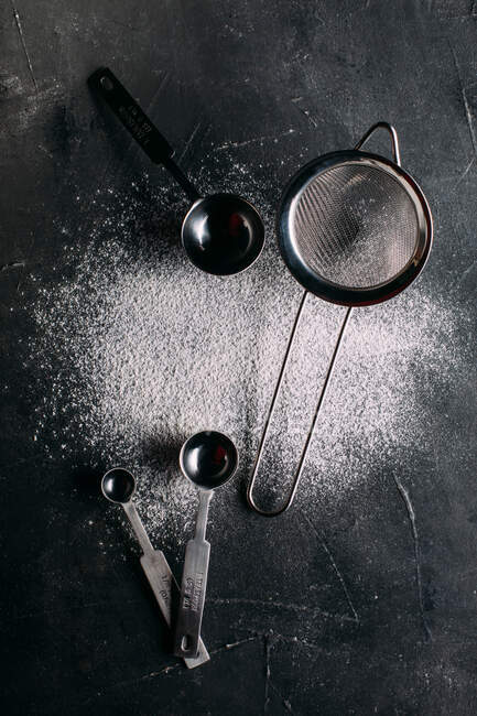Flour and strainer over dark background — Stock Photo