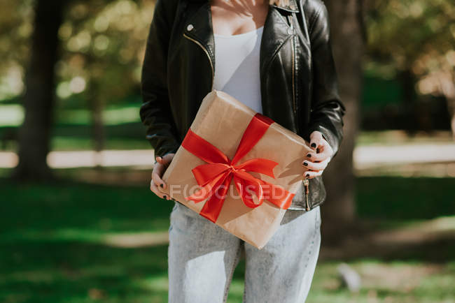 Midsection de mulher segurando presente embrulhado com fita vermelha — Fotografia de Stock