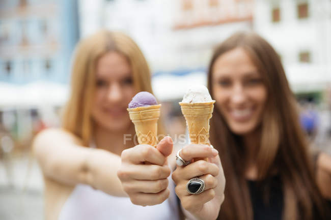 Портрет веселых девушек, показывающих рожки мороженого перед камерой — стоковое фото