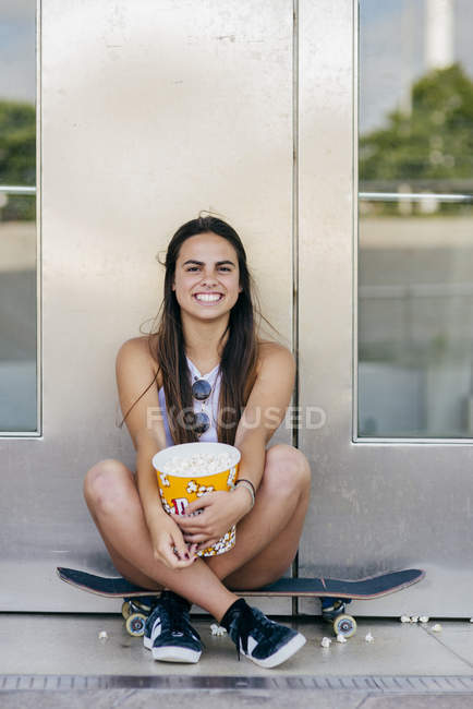 Encantadora chica con palomitas de maíz en el patín - foto de stock