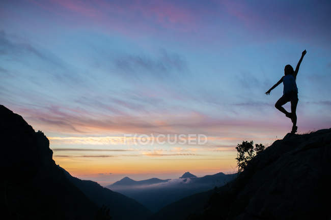 Силуэт девушки, стоящей на скале — стоковое фото