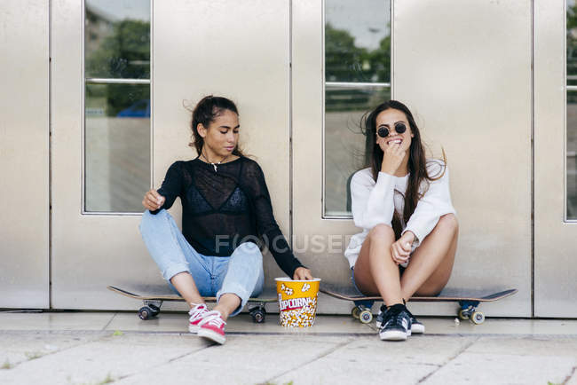 Les adolescents élégants avec du pop-corn sur les patins — Photo de stock