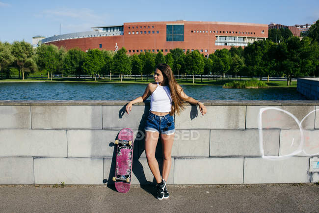 Стильный подросток позирует со скейтом — стоковое фото