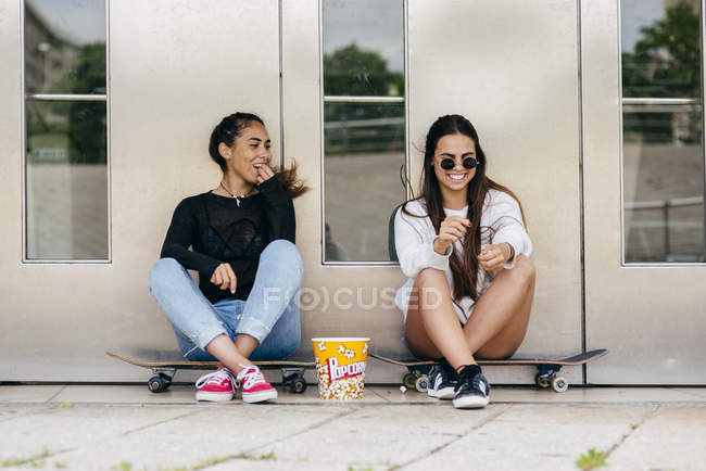 Adolescentes con estilo con palomitas de maíz en patines - foto de stock