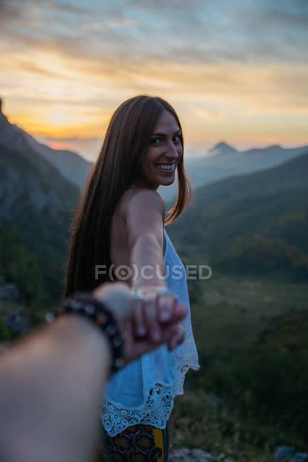 Folge mir im Stil Porträt eines lächelnden brünetten Mädchens, das in die Kamera schaut und die Hand hält. — Stockfoto