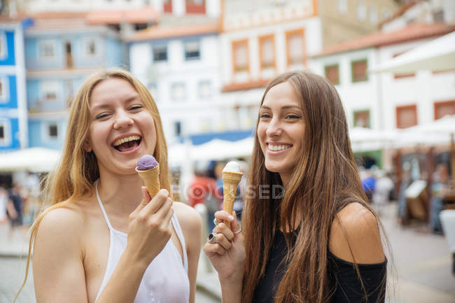 Portrait of laughing cheerful girls eating ice cream at street — Stock Photo