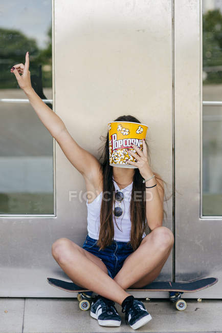 Adolescent couvrant visage avec seau de maïs soufflé — Photo de stock