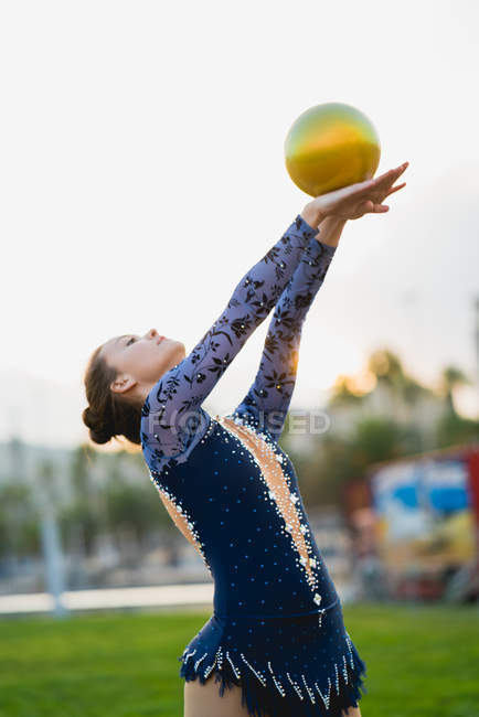 Гімнастка, тримаючись за руки з м'ячем — стокове фото