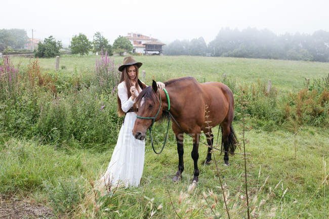Girl  stroking brown horse — Stock Photo