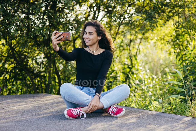Sonriente chica tomando seflie en parque - foto de stock