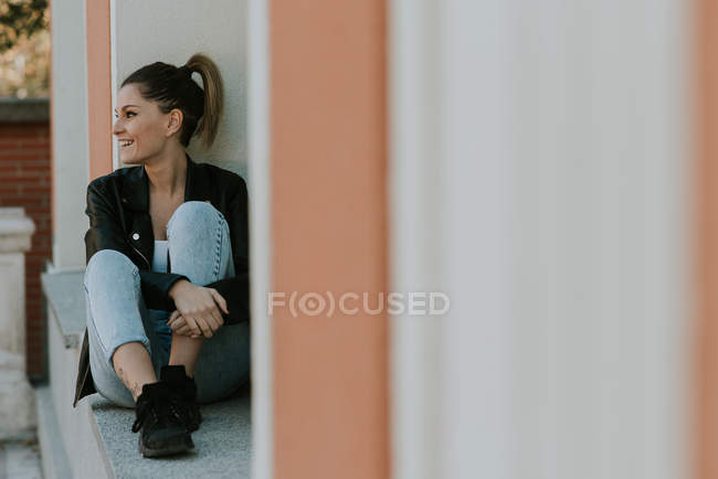 Young girl sitting on window sill and looking away — Stock Photo