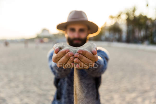 Macho extendiendo las manos con arena - foto de stock
