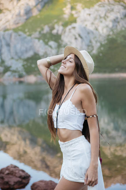 Portrait of happy brunette woman with eyes closed posing against of mountain lake on backdrop — Stock Photo