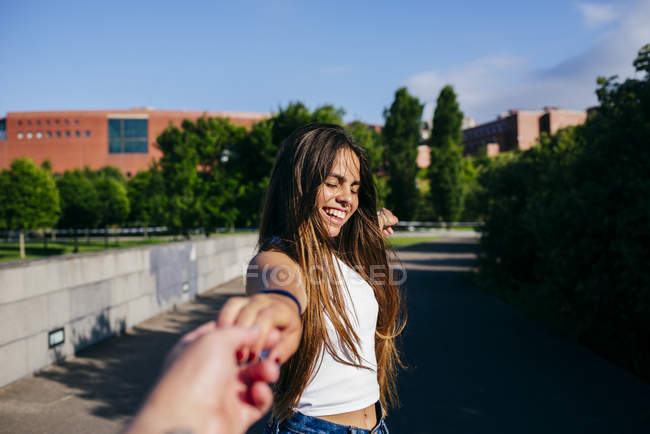 Chica sosteniendo la mano anónima y sonriendo - foto de stock