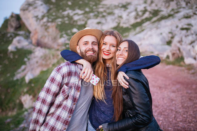 Tres amigos abrazándose en la montaña - foto de stock
