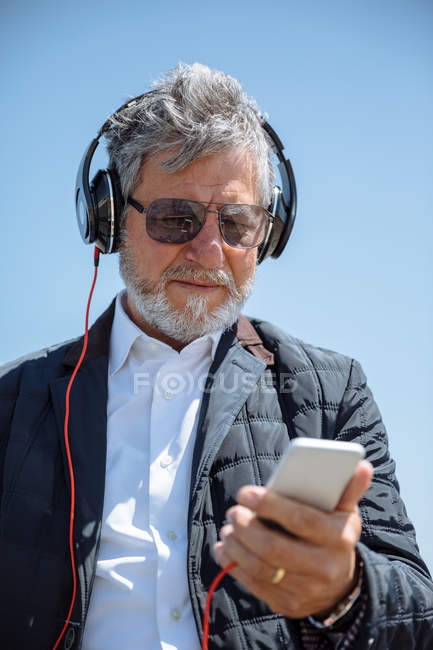 Homme âgé avec casque et smartphone — Photo de stock