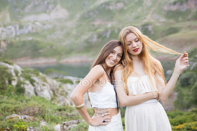Retrato de novias sonrientes abrazándose por el lago de montaña - foto de stock