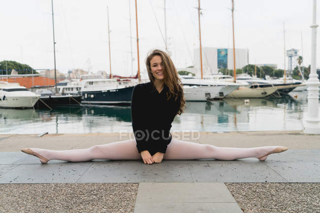 Молодая балерина делает сплит и улыбается — стоковое фото