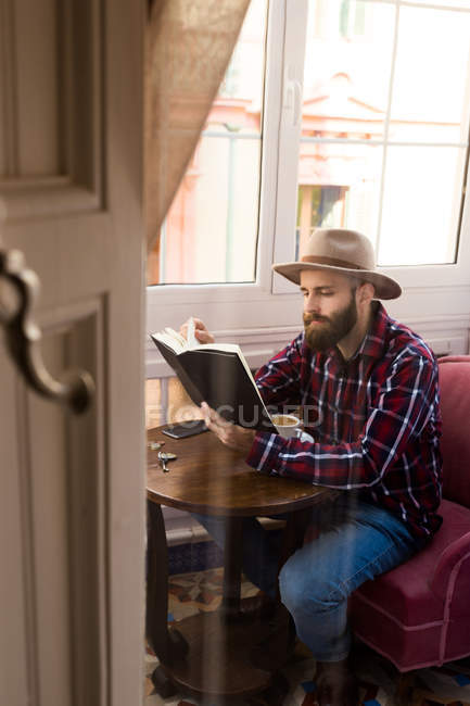 Joven hombre con libro en la cafetería - foto de stock
