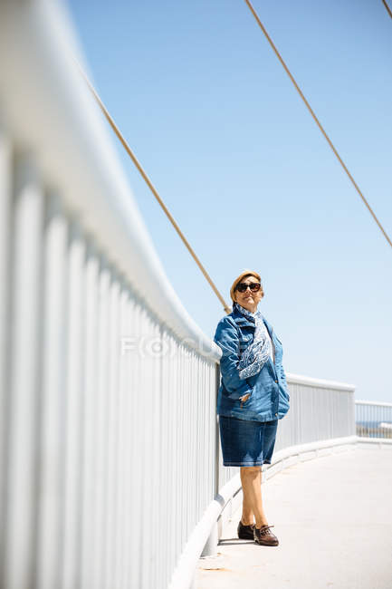 Senior woman leaning on fence — Stock Photo