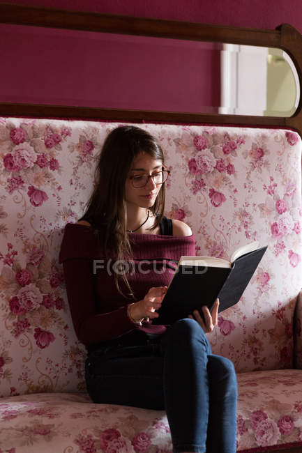 Donna con libro sul divano — Foto stock