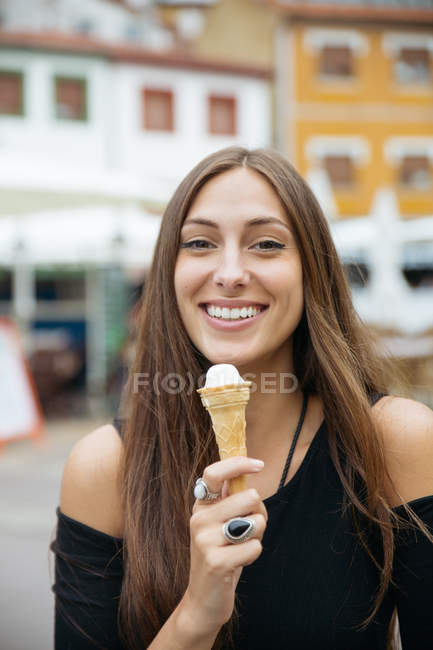Retrato de chica morena sosteniendo helado y mirando a la cámara - foto de stock
