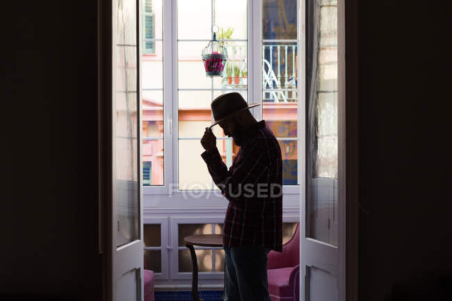 Hombre en sombrero de pie en la puerta - foto de stock