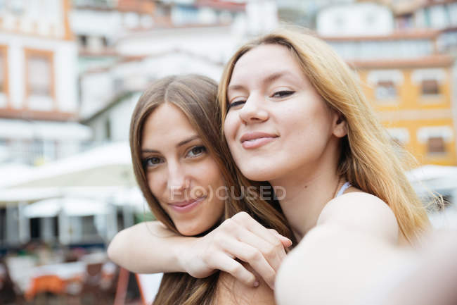 Dos novias tomando selfie mientras abrazan y sonríen - foto de stock
