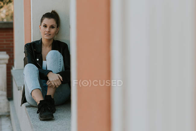 Young girl sitting on windowsill and looking at camera — Stock Photo