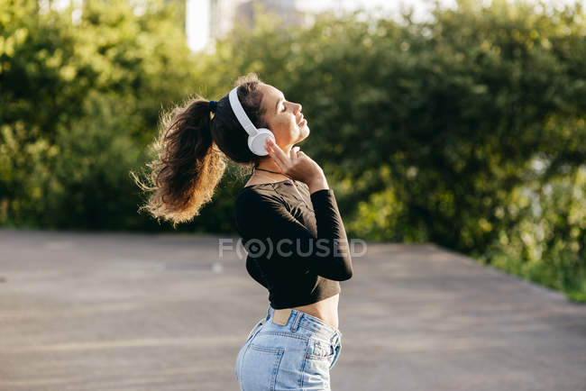Contenido chica escuchando música fuera - foto de stock