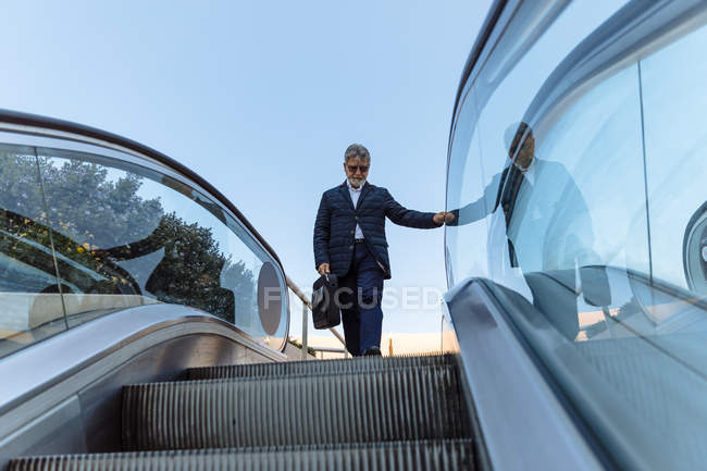 Homme descendant les escaliers mécaniques — Photo de stock