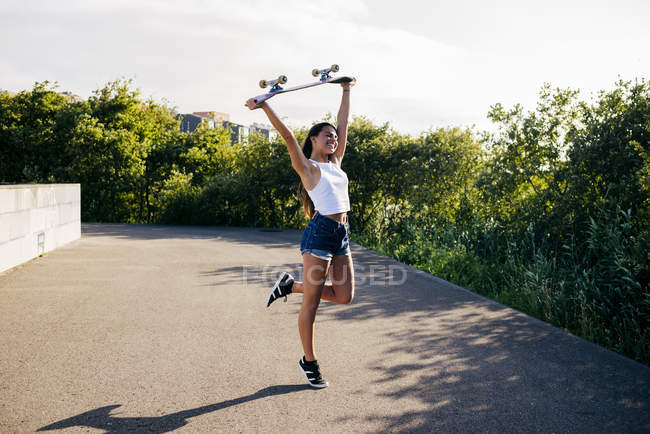 Happy girl holding skate above head — Stock Photo