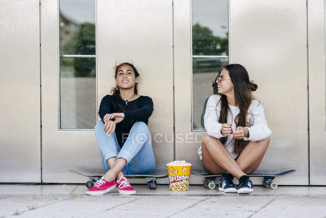 Adolescentes con estilo con palomitas de maíz en patines - foto de stock