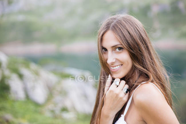 Souriante fille brune en robe blanche posant au lac de montagne — Photo de stock