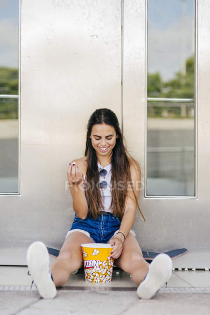 Chica alegre posando con palomitas de maíz - foto de stock