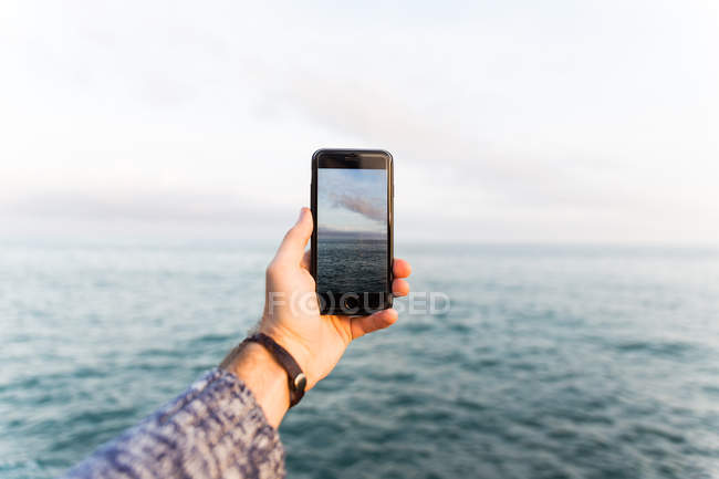 Homme prenant des photos de la mer — Photo de stock