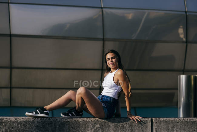 Elegante ragazza ridente seduta sul cemento — Foto stock