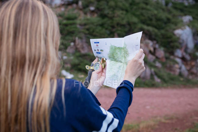 Girl using compass and map on mountain road — Stock Photo