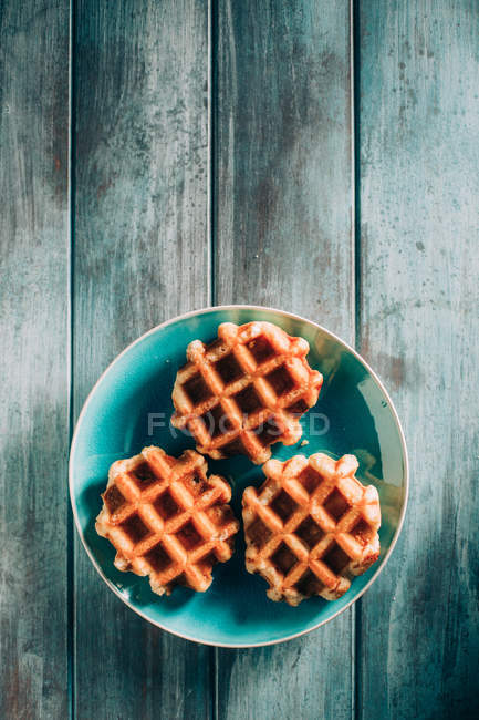 Waffles in dish over grunge wood — Stock Photo