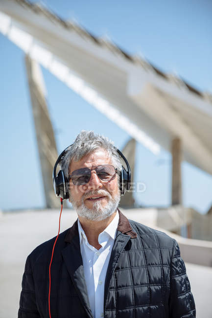 Старший чоловік в сонцезахисних окулярах і навушниках — стокове фото
