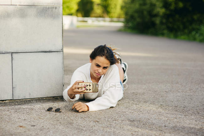 Adolescente de moda en el pavimento tomando selfie - foto de stock